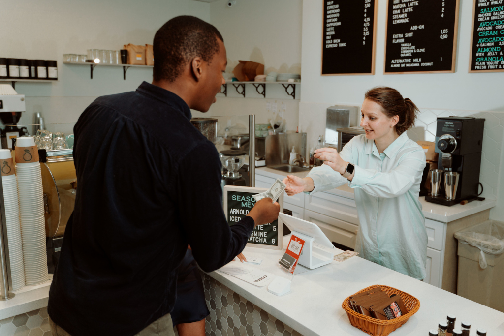 A customer pays for a service at a café counter.
