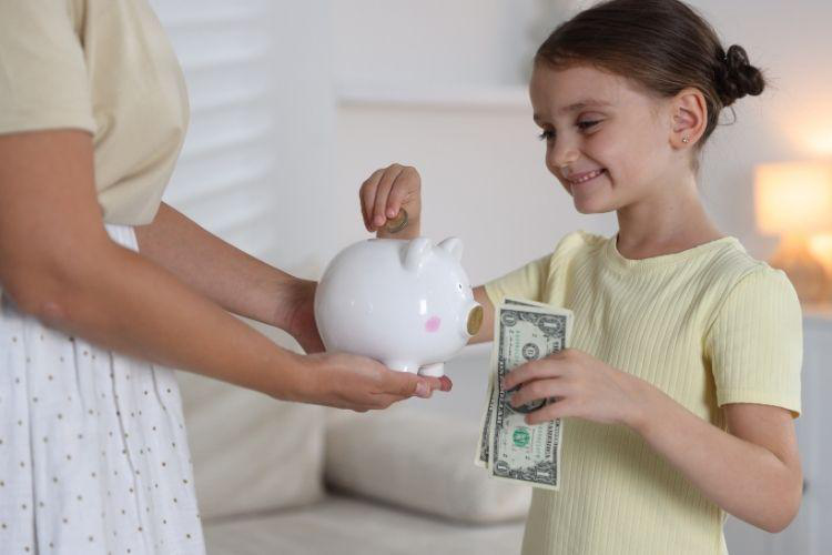 Mother and Daughter Putting Money into Piggy Bank