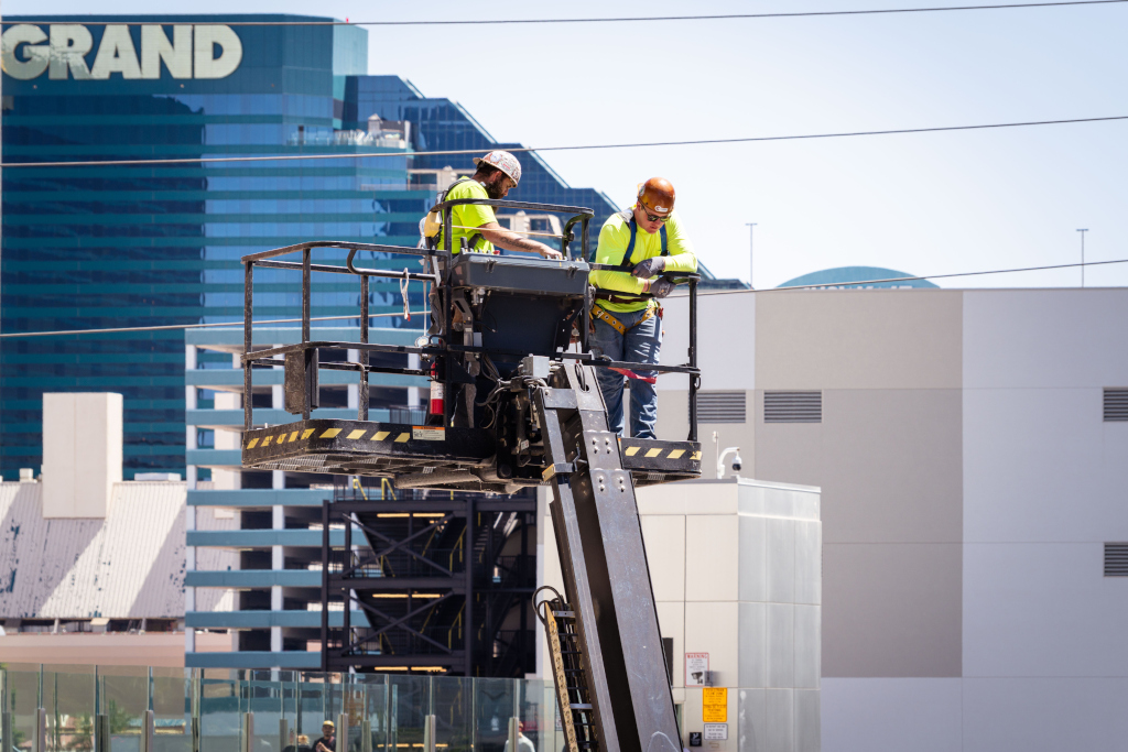 Construction workers perform exterior maintenance on a high-rise.